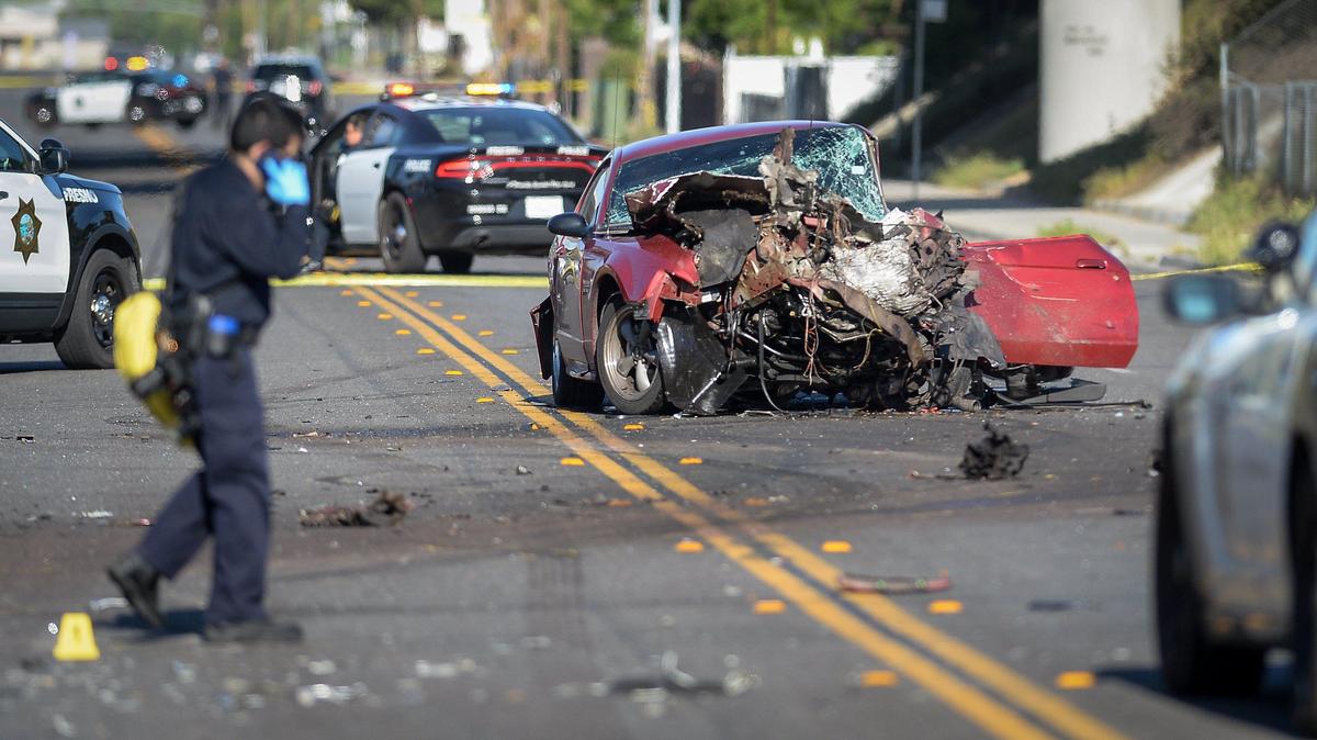A vehicle involved in a police pursuit and fatal crash stands in the roadway at Olive Avenue near Cedar in Fresno as police investigators examine the scene in 2020.