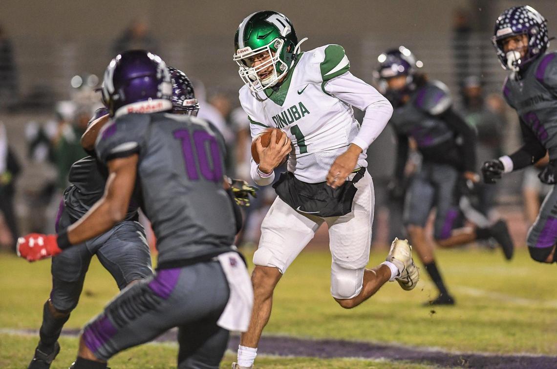Dinuba quarterback Sebastian Olivera, center, runs into the Washington Union secondary on a keeper in their Central Section Division II playoff game at Jesse Ventura Stadium in Easton on Friday, Nov. 4, 2022.