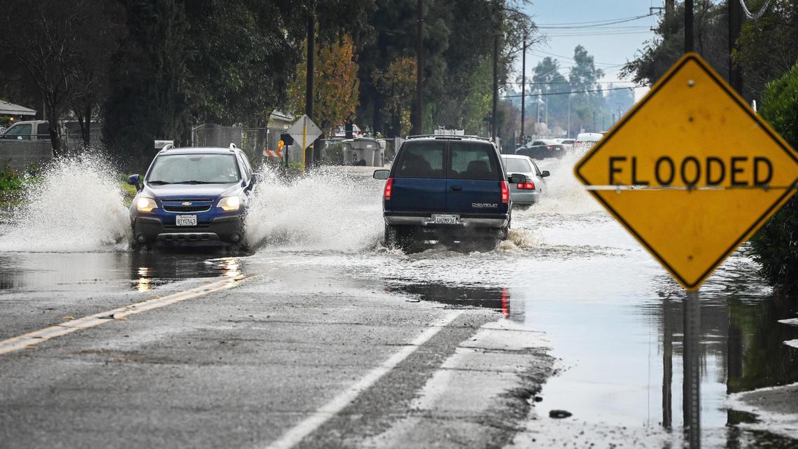 Cars drive through a flooded section of Valentine Avenue north of Clinton in west Fresno on Dec. 14, 2021. Another series of storms is expected to bring rain to Fresno and the San Joaquin Valley starting Tuesday, Dec. 21 and continuing through Christmas Day, with snow possible at higher elevations in the Sierra Nevada.