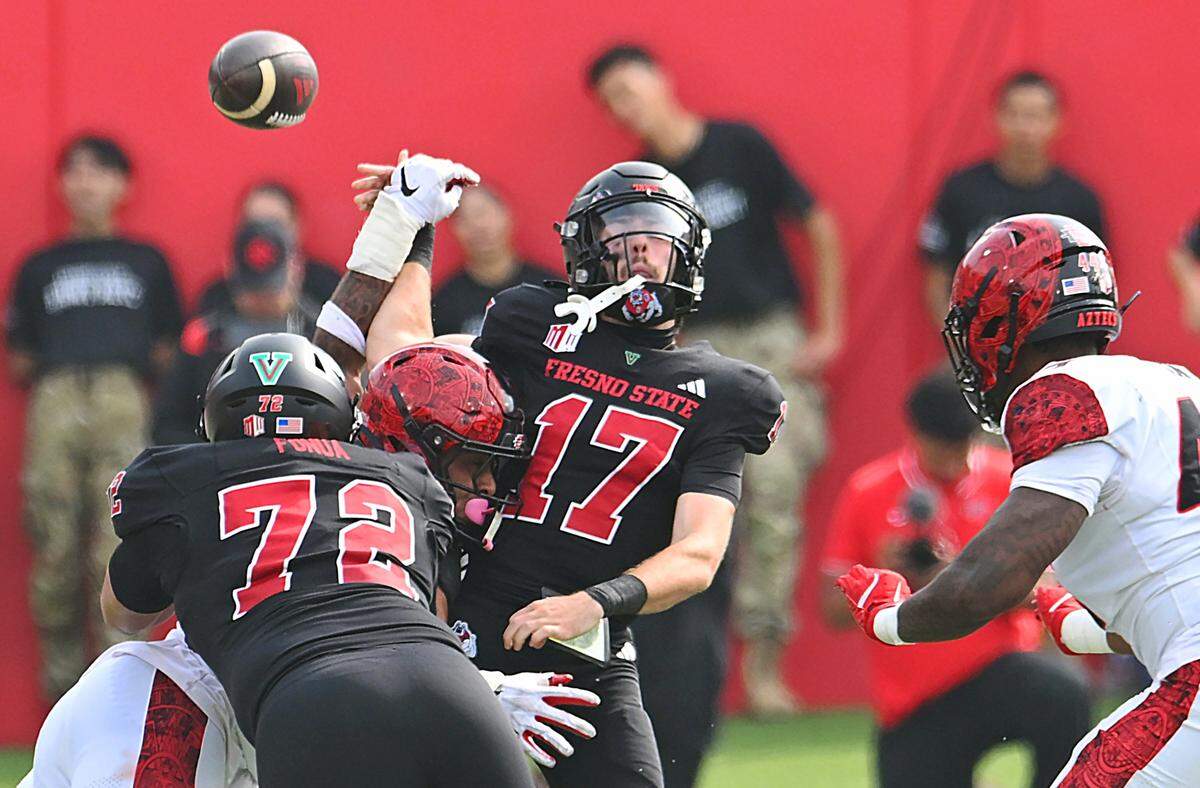 The ball flies loose as Fresno State's quarterback Carson Conklin, center, is hit by San Diego State's Trey White, left, Saturday, Oct. 24, 2025 in Fresno. 