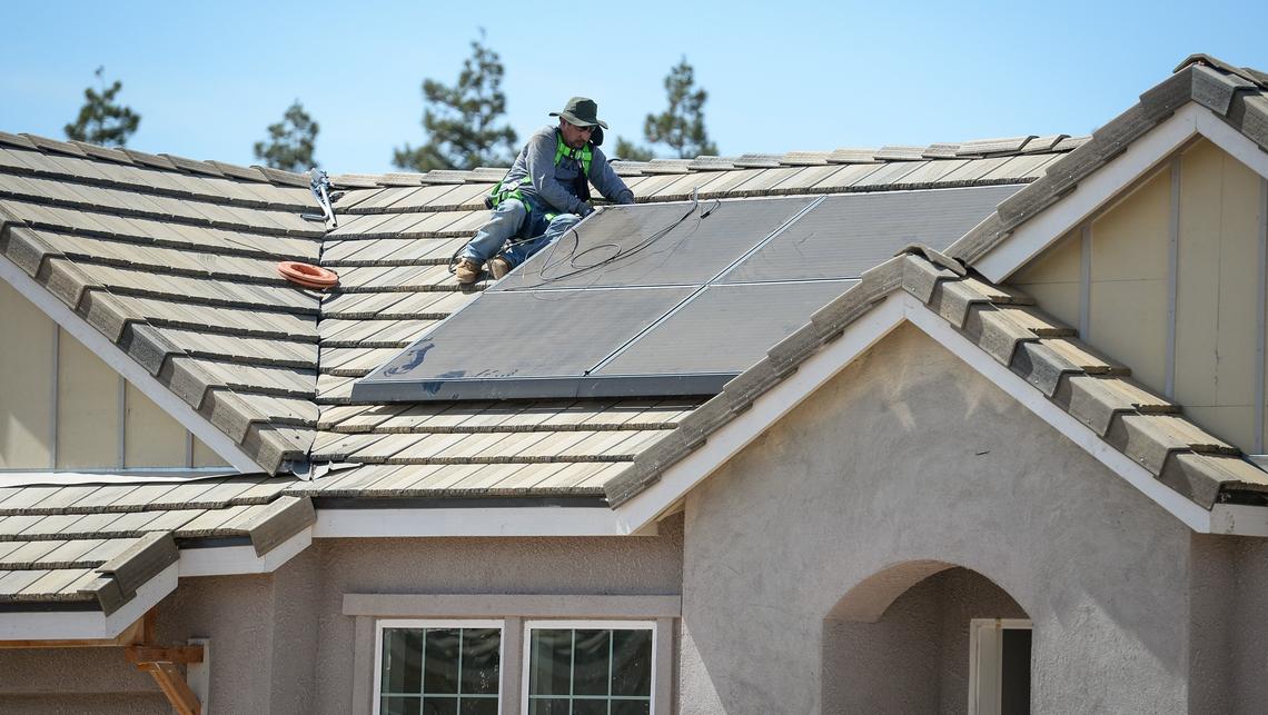 A worker installs Telsa soar panels on a De Young Properties home at the company’s Envision community east of Clovis, on Thursday, July 5, 2018.