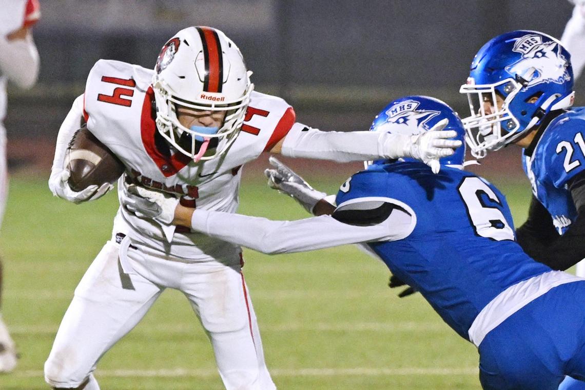 Kerman’s Xavier Montalvo, left, breaks a block by Madera’s Gavin Castro, right, in the Central Section DIII championship held Friday, Nov. 29, 2024 in Madera. Kerman won the championship game beating Madera 42-28.