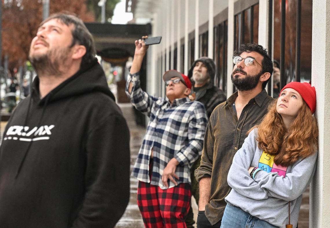 Interested onlookers watch as workers attach crane cables to the G sign on top of the Guaratee Bank building, owned by the State Center Community College District, before attempting to lift it off its supports in downtown Fresno on Saturday, Jan. 20, 2024. The operation was halted due to issues with removing the 60-year-old sign from its supports and will be attempted again in a few weeks, SCCC officials said.