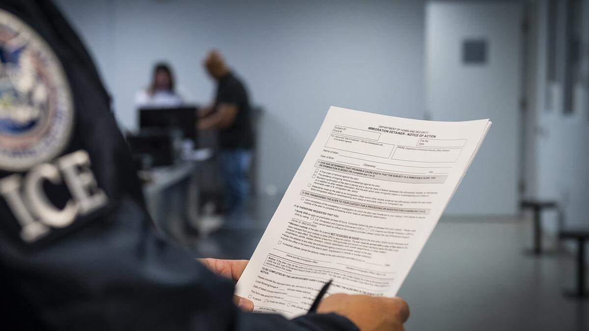 A federal immigration agent holds an immigration detainer form at a detention facility.