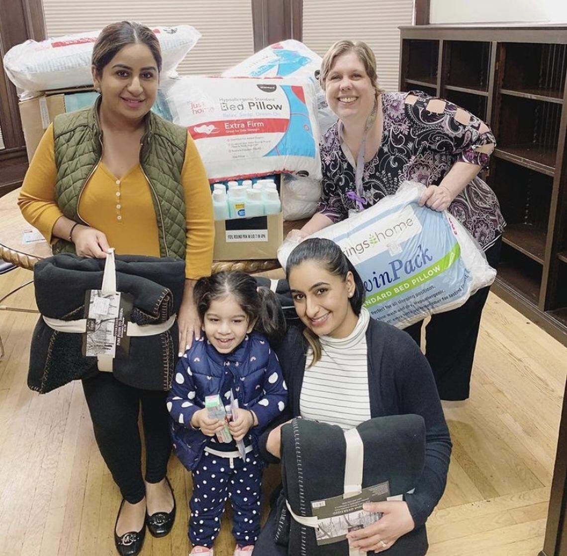 Sisters. Geeta Dhugga, left, and Roma Dhugga, right, pose with a family they helped support with supplies and a donation.