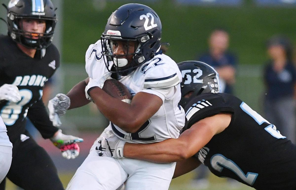 Clovis East’s Lamaj Travis, center, is tackled by Clovis North’s Mario Gonzalez, right, Friday, Sept. 30, 2022 in Clovis.