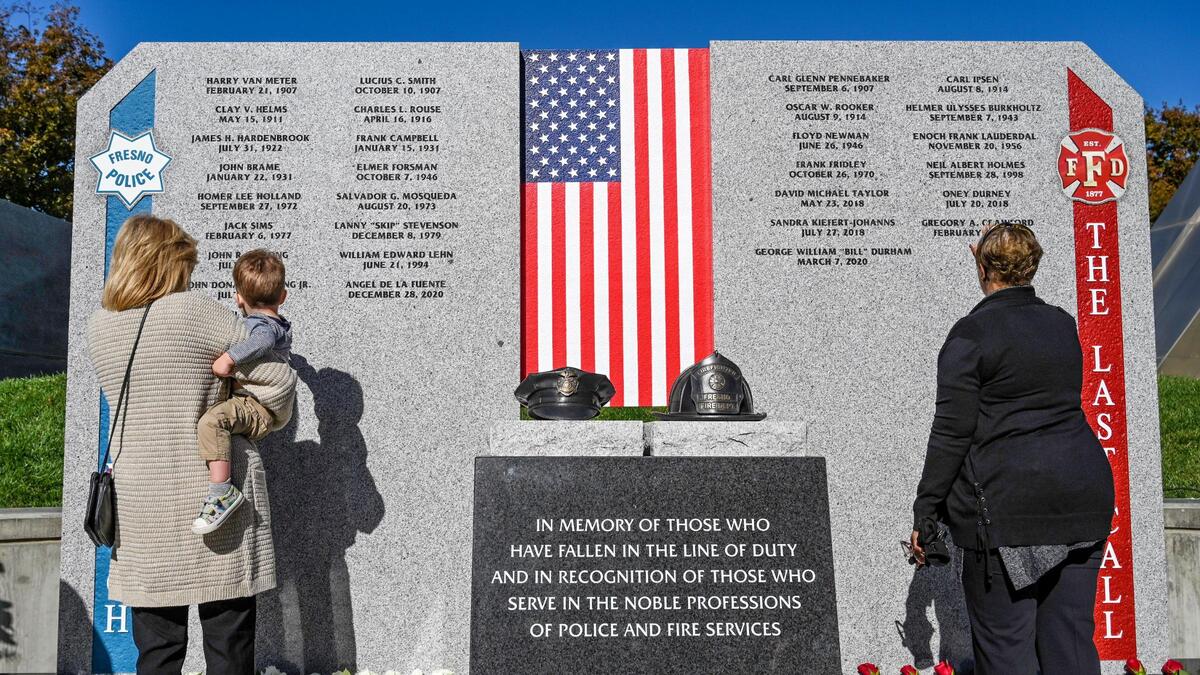 Family members take a close look at the names inscribed on the new First Responders Memorial honoring city police officers and firefighters who lost their lives after an unveiling ceremony outside Fresno City Hall on Wednesday, Nov. 2, 2022.