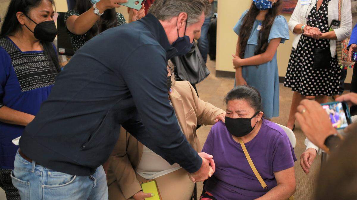 El gobernador de California, Gavin Newsom, a la izquierda, sostiene la mano de Lorenza Cortez Barrera, a la derecha, cuando se va después de hablar con ella y otros ex trabajadores agrícolas en la Clínica Sierra Vista el martes 27 de julio de 2021 por la mañana en Fresno, CA. Barrera, de 63 años, es ciega y depende de su esposo Eleuterio Mexicano Gonzalez, de 68 años, para que la cuide en el hogar.