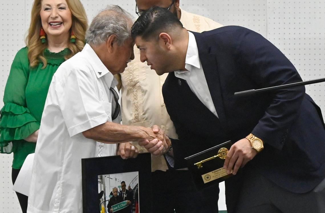 El presidente del Comité César Chávez, Venancio Gaona, a la izquierda, estrecha la mano del concejal de Fresno Luis Chávez, después de recibir un premio durante la celebración del cambio de nombre de la calle en el recinto ferial de Fresno, el sábado 10 de junio de 2023, en Fresno.