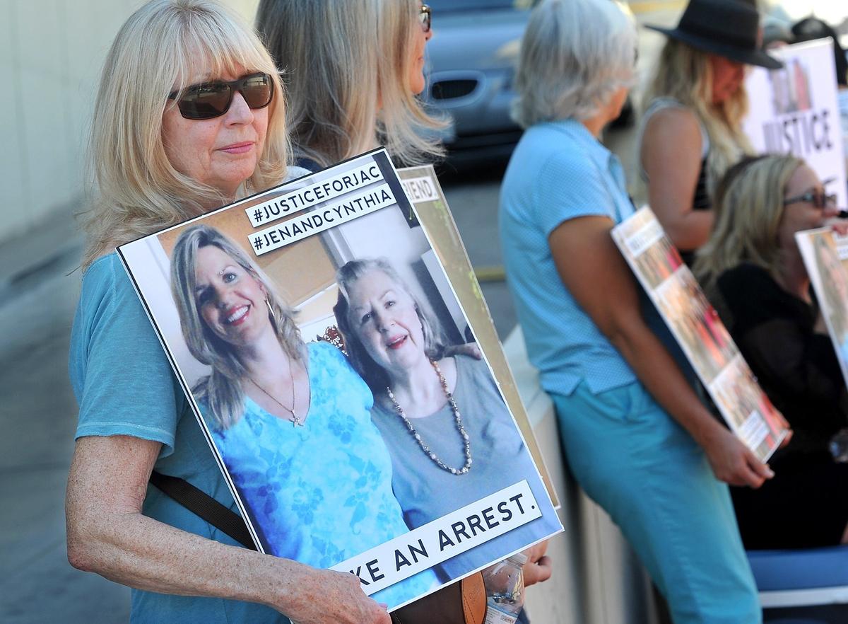 Ginny Federico holds a poster-with the message, Make An Arrest- of her friends, Jennifer Dupras, at left, and Cynthia Houk, at right, mother and daughter, who were killed in December during a silent protest with family and friends outside the Fresno County District Attorney’s office, Monday morning, July 23, 2018.