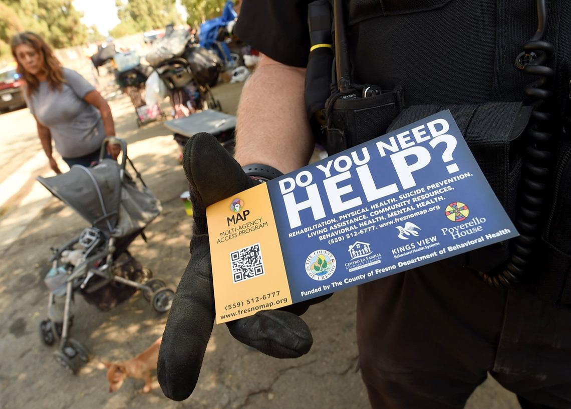 Officer Gary Holden shows a card that police hand to homeless people offering assistance when they do their daily cleanups of their camps.