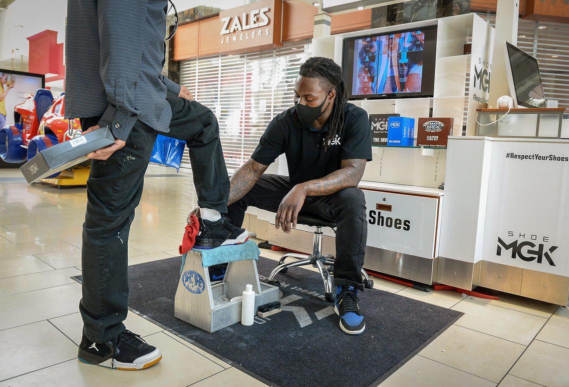 Chris Nsele of Shoe MGK cleans a customer’s shoes after opening in a kiosk at Fashion Fair Mall on Tuesday, May 26, 2020. Nsele, like many other mall workers, returned to work for the first time since the mall closed late March due to the coronavirus pandemic.