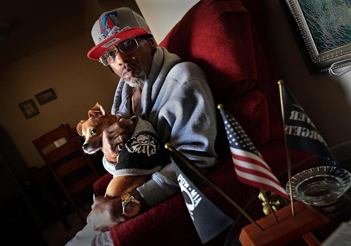 Disabled Army veteran Claudio Hughes sits with his dog, Bones, in his home at Manchester Arms Apartments in Central Fresno, Feb. 17, 2021. He says he has had many issues with management over such things as going recently without a stove for 68 days-Thanksgiving was a chicken pot pie he and his brother shared- to water being shut off, several times he said without warning, and trying to restrict who he can visit his apartment.