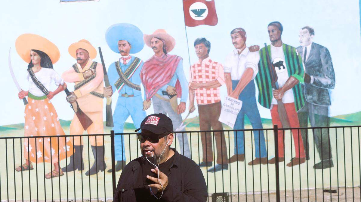 Hugo Hopping tapes an audio in front of the resurrected mural that his father, Antonio Bernal, drew in 1968 while a member of Teatro Campesino in Del Rey. A memorial ceremony for Bernal was held Oct. 22, 2023.