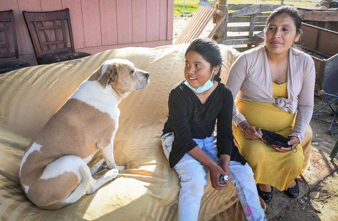 Laura Garcia sits with her daughter Kenia, 8, and their family dog Chula at their home in the rural Fresno County community of Raisin City on Friday, Feb. 12, 2021. Laura is a mother of 5, with one on the way, and is concerned about how the air quality due to nearby burns is affecting her kids. Kenia has asthma.