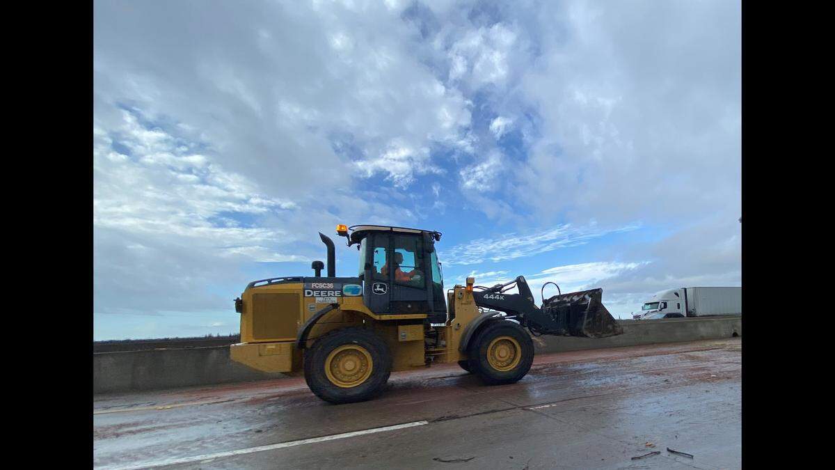 A Caltrans worker cleans debris from Highway 99 after a double fatal crash Tuesday, Jan. 10, 2022, caused by a tree that fell and caught fire after it was struck by lightning in Goshen, the California Highway Patrol said.
