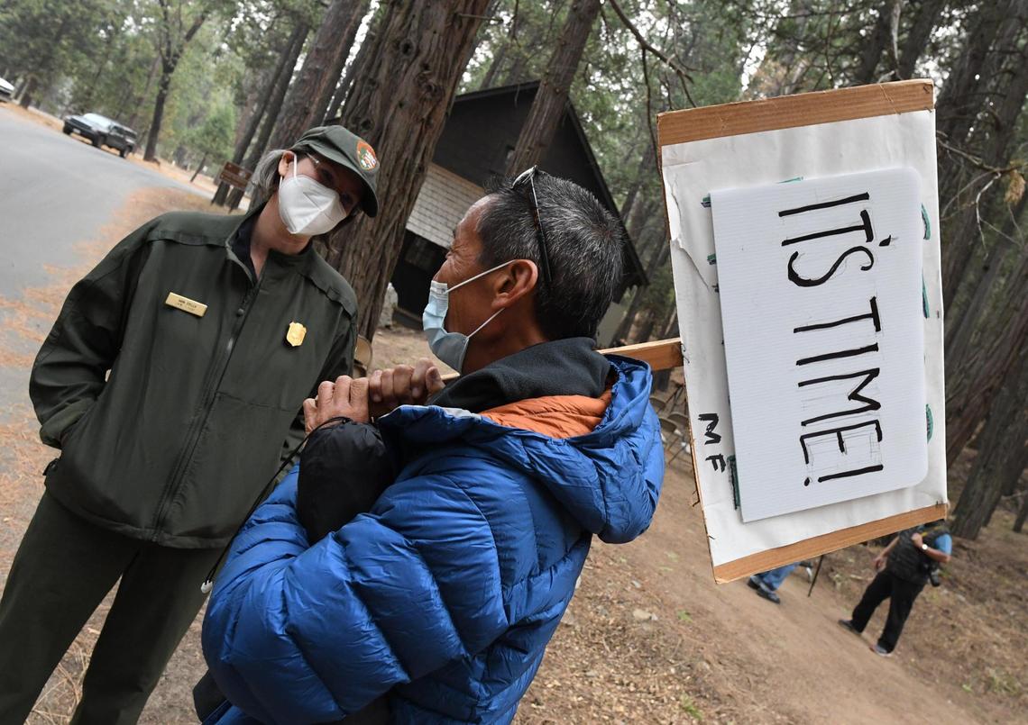 Eric Leong of San Francisco expresses his feelings in his sign, as he talks with Yosemite Park Ranger Kara Stella, before dedication of the 1917 Chinese laundry building at Wawona, Friday, Oct. 1, 2021. The building, principally was used to service the Wawona Hotel, was also used in various purposes over the years and is being rededicated to tell the story of Chinese American contributions to Yosemite’s history.