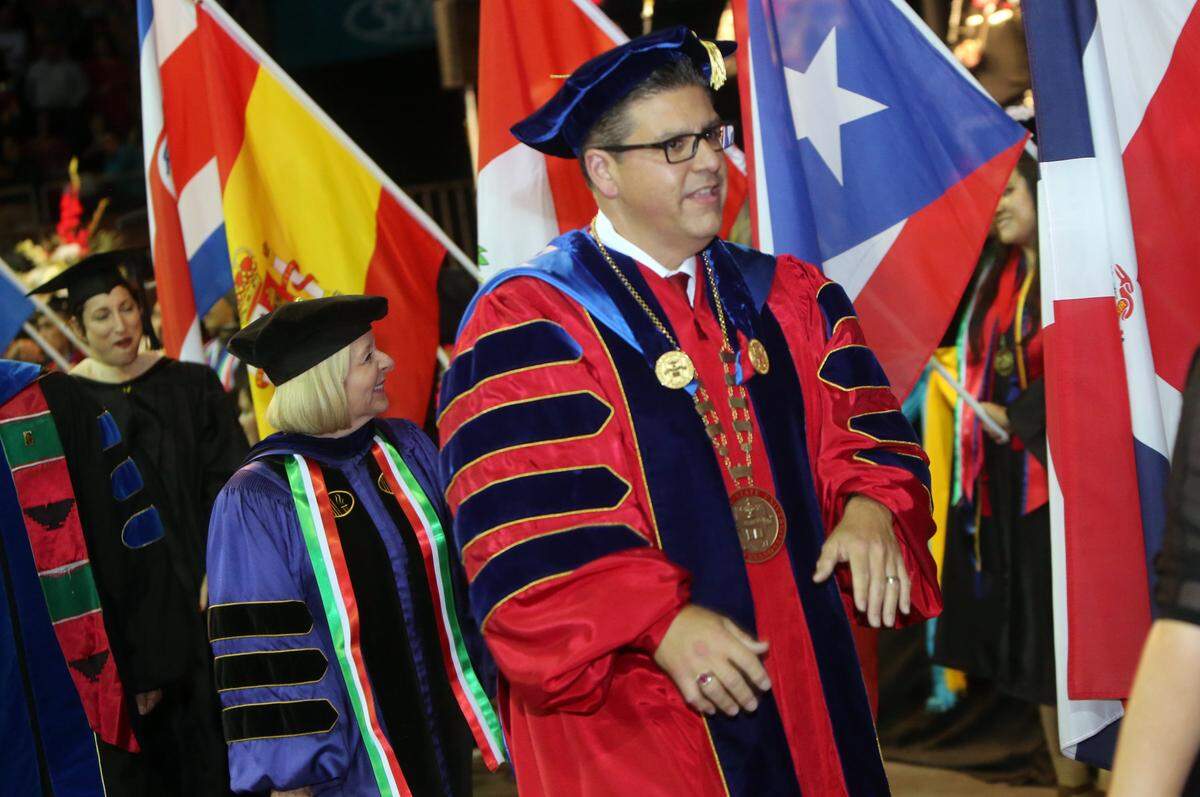 Fresno State President Joseph I. Castro walks past the display of flags during the 42nd annual Chicano/Latino Commencement Celebration May 19, 2018, at the Save Mart Center.
