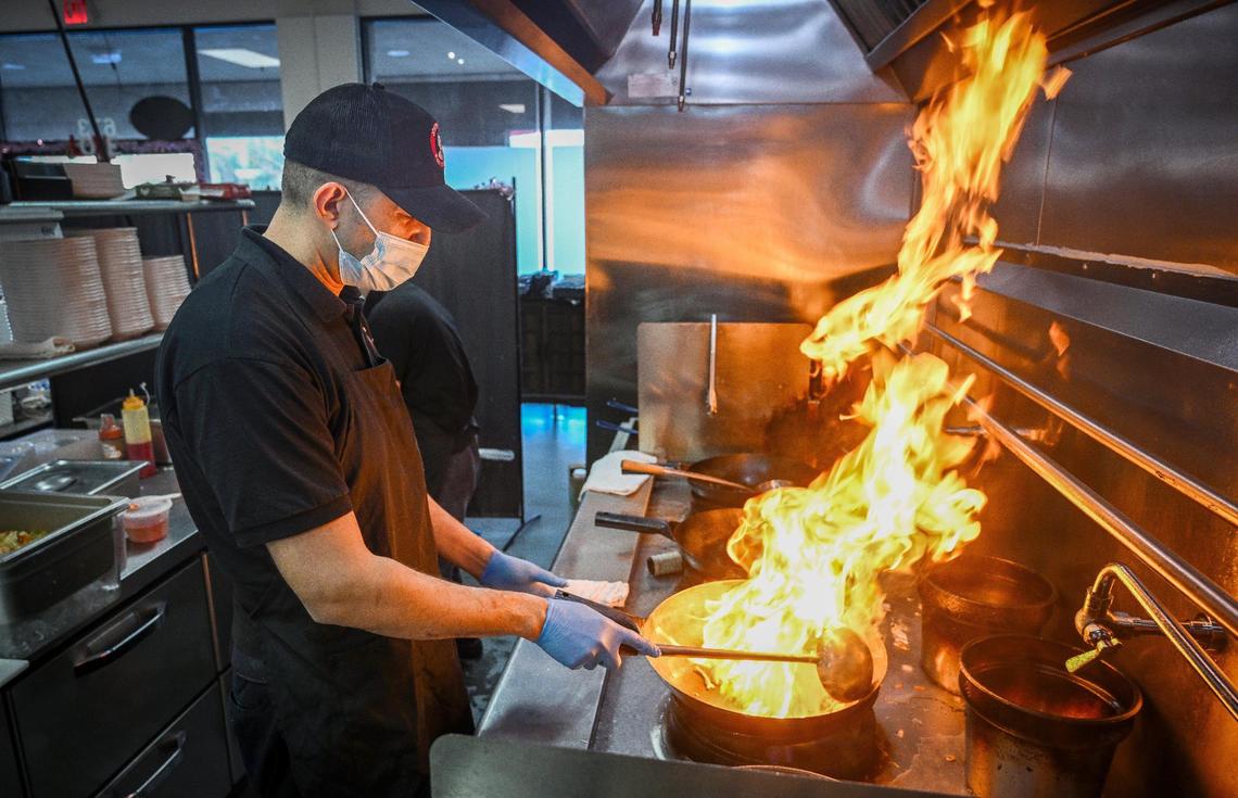 Flames leap from the wok as Assistant manager Armando Martinez cooks up an order at Paik’s Noodle in north Fresno on Monday, Jan. 27, 2025