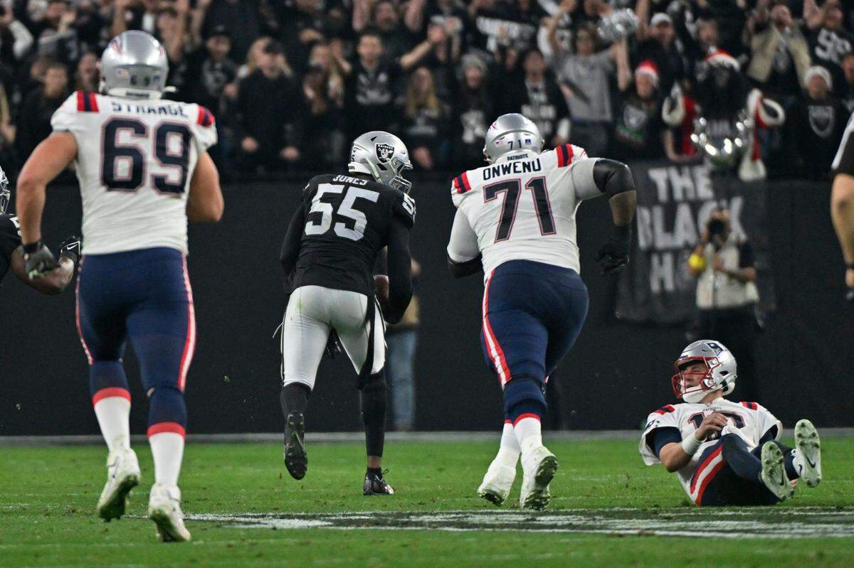 New England Patriots quarterback Mac Jones watches as Las Vegas Raiders defensive end Chandler Jones runs for a touchdown after an interception during the second half of an NFL game between the New England Patriots and Las Vegas Raiders, Sunday, Dec. 18, 2022, in Las Vegas. The Raiders defeated the Patriots 30-24.