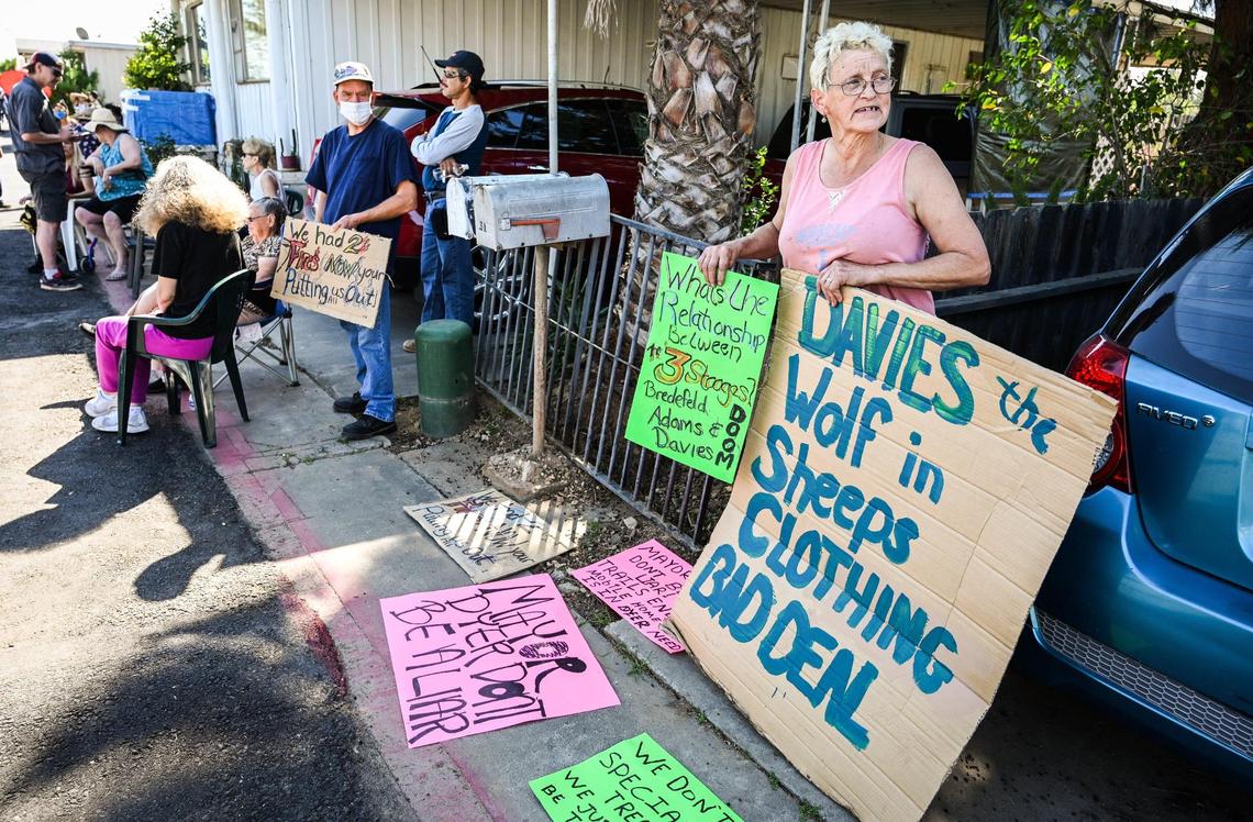 Trails End Mobile Home Park resident Patricia Shawn holds up signs protesting the possible sale of the park to Harmony Communities, as Fresno Mayor Jerry Dyer and Fresno City Councilmember Garry Bredefeld arrive to speak to residents on Friday, March 25, 2022.