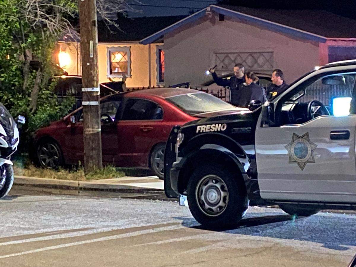 Officers investigate a vehicle that crashed between a pole and a tree following a collision that killed a woman and injured a man on Friday, May 3, 2024.