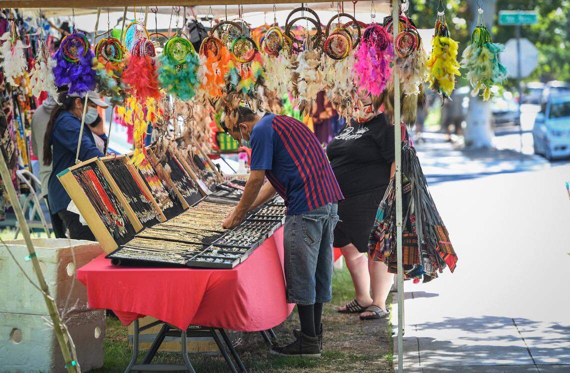 Customers check out merchandise being sold at a booth near Harvard and Van Ness avenues during the annual Harvard block sale in Fresno on Saturday, July 11, 2020. The sale was moved from May due to the coronavirus pandemic, but was still discouraged by city officials.