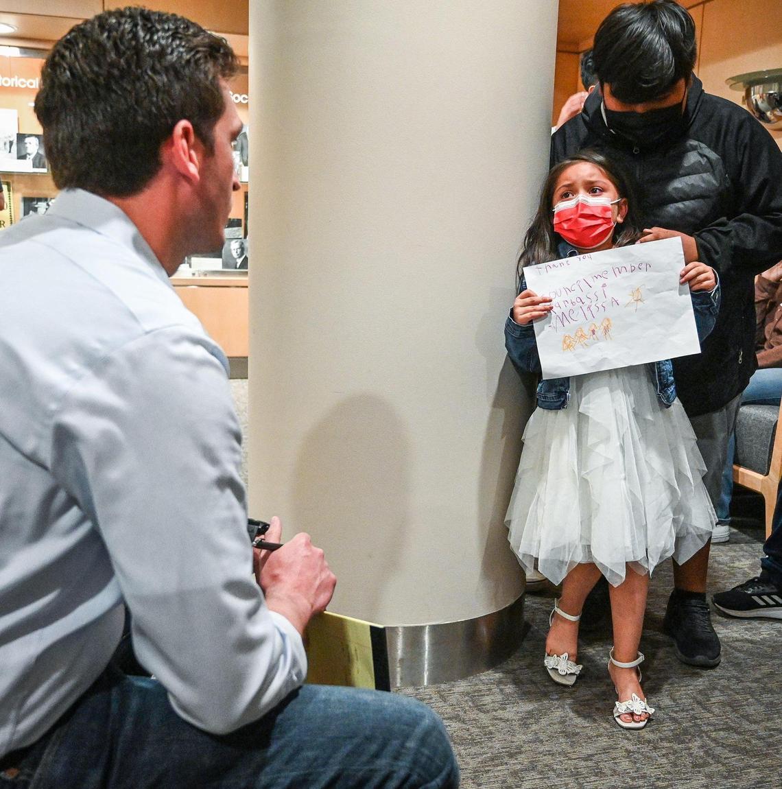 Johnathon Burrows, left, a public relations assistant with Fresno City Councilmember Nelson Esparza’s office, listens to Melissa, a child living in the Trails End Mobile Home Park, who shows a picture she drew for Councilmember Mike Karbassi at Fresno City Hall on Tuesday, April 6, 2022. On Tuesday, residents, their children and advocates of the mobile home park walked into the lobby of city leaders to plead for help in blocking the sale of the park to Harmony Communities.