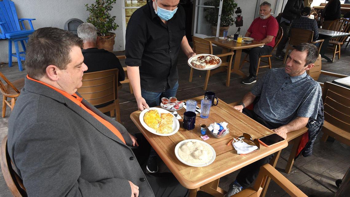 Customers Michael Graville, left, and Jason Long, right, are served breakfast outdoors at Sandy’s Country Junction in Old Town Clovis, in this file photo from Tuesday morning Nov. 16, 2020.