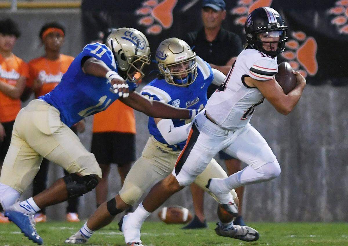 Central quarterback Dayton Tafoya, right, scrambles away from Clovis High’s defense Tovie Martin, left, and Nate Reinhold, center, in first quarter action Thursday, Sept. 29, 2022 in Clovis.