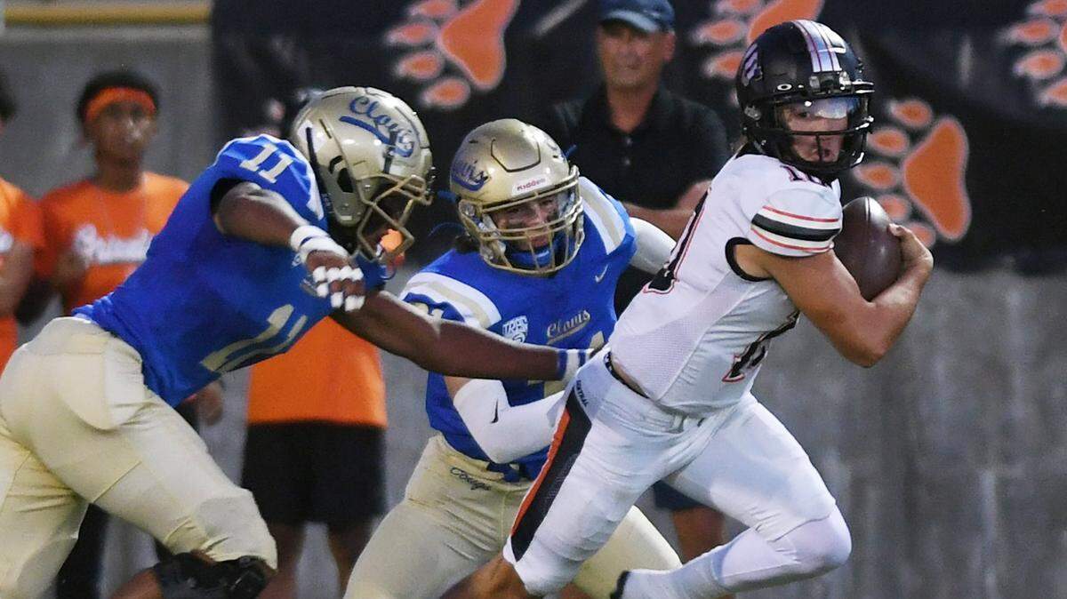 Central quarterback Dayton Tafoya, right, scrambles away from Clovis High’s defense Tovie Martin, left, and Nate Reinhold, center, in first quarter action Thursday, Sept. 29, 2022 in Clovis.