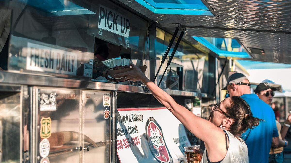 A customer picks up food at a food truck event in 2020. Fresno Street Eats will begin hosting food trucks at Manchester Center Friday, March 5. Real Philly, Brickology, Rubia’s Churros, Get Baked and Taqueria Jalisciense will be participating in the first one.