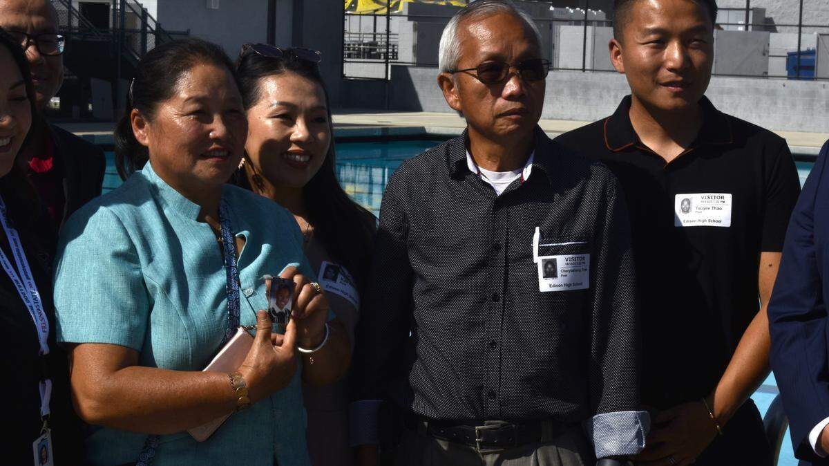 Chong Vang (left, blue) holds a picture of her youngest son, Neng Thao, while standing with members of her family for a photo at Edison High School on Friday, Oct. 13, 2023. The Thao family met with Fresno Unified School District leaders and State Assemblymember Joaquin Arambula to celebrate the passing of AB 1445, the Neng Thao Drowning Prevention Bill, which honors her son. Neng Thao drowned in May 2017 two weeks before graduating as an Edison valedictorian student.