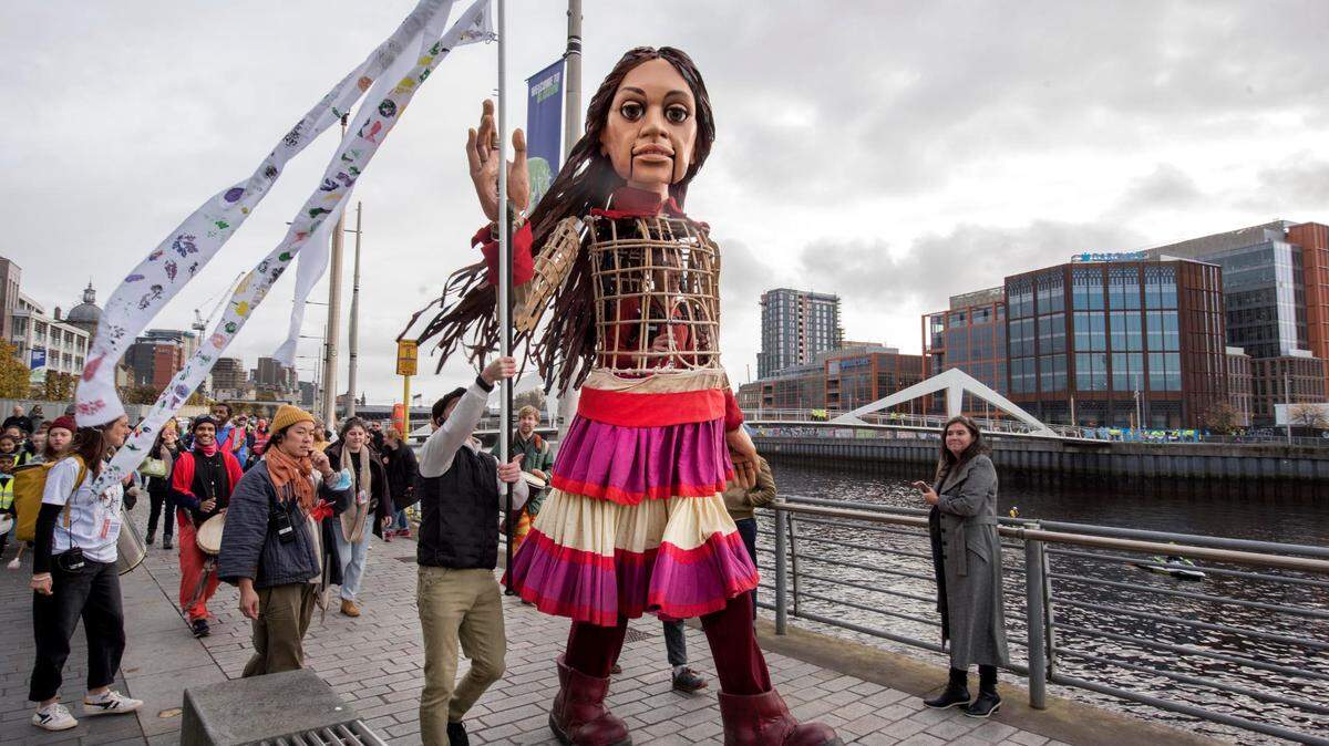 Amal, una marioneta de 3.6 metros de altura que encarna una niña siria de 10 años que dejó su país en busca de su madre que emigró hacia el Reino Unido, camina junto a personas por las calles de Glasgow, Escocia. Amal visitará a partir de este jueves EE.UU., incluidos varios estados de la frontera con México, para “humanizar la migración”.
