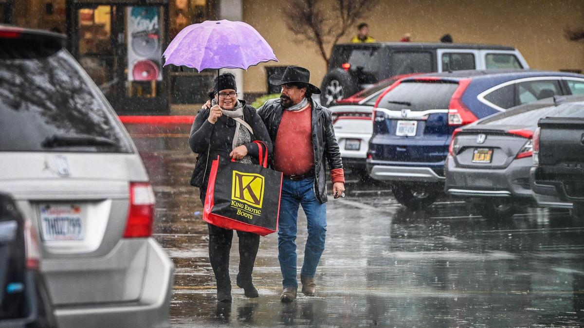 A couple walks through the Fashion Fair mall parking lot to their car as the rain continues to fall on a wet Tuesday afternoon, Dec. 27, 2022.