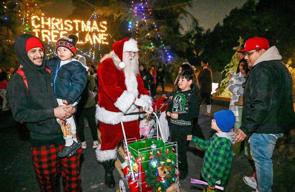 Santa hands out candy canes as holiday revelers enter Christmas Tree Lane north of Shields in Fresno on the first of two walk-only nights on Tuesday, Dec. 3, 2024.