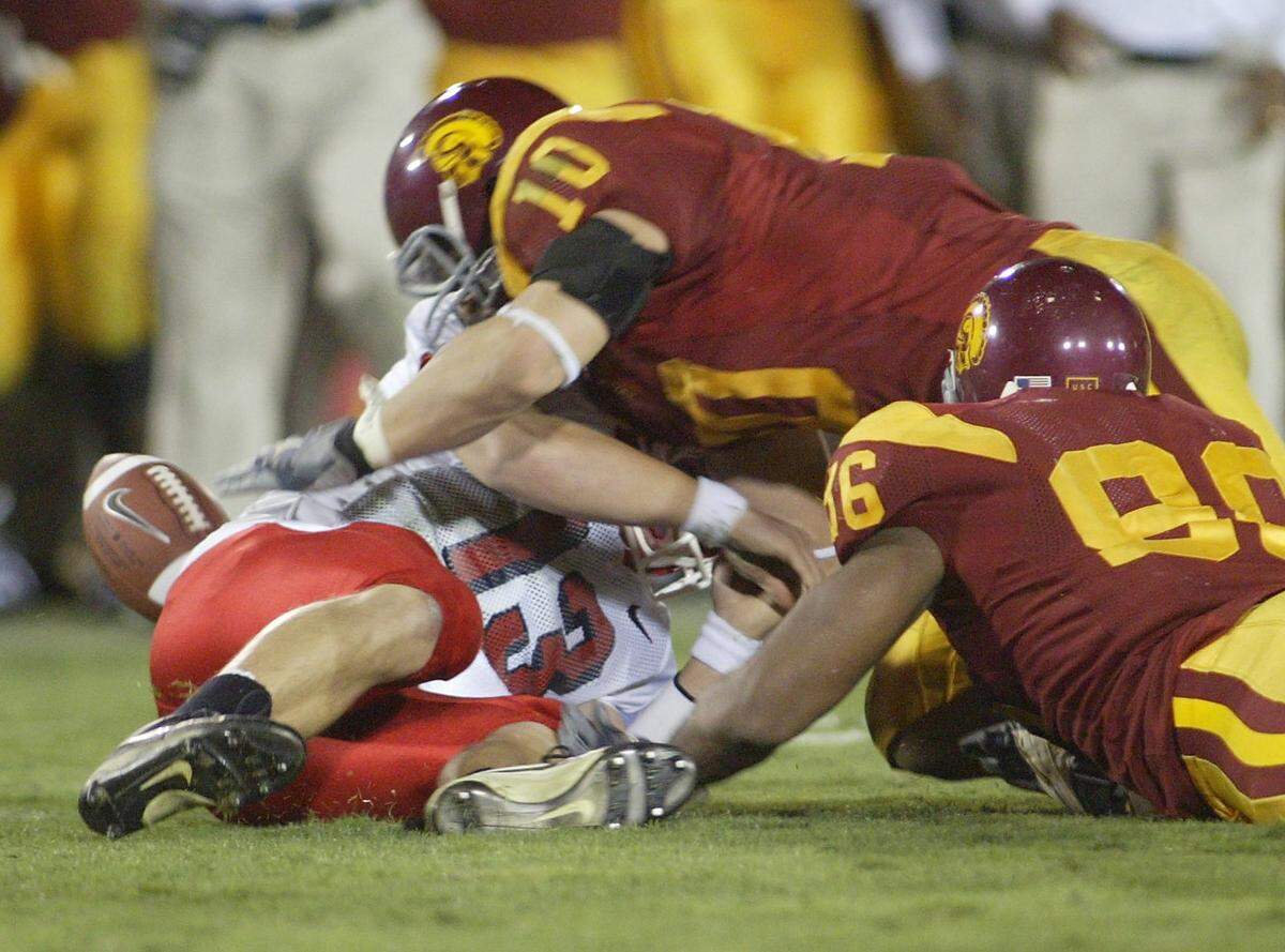 Fresno State quarterback Paul Pinegar fumbles the ball after being hit by USC's Lawrence Jackson, right, as USC's Brian Cushing, #10, goes for the loose ball. The turnover came deep in Bulldog territory.