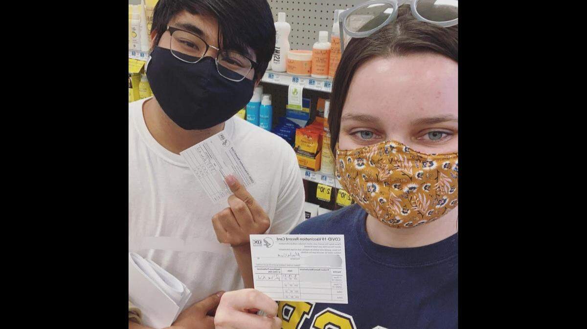 Madeline Thompson and her friend show their COVID-19 vaccination cards.