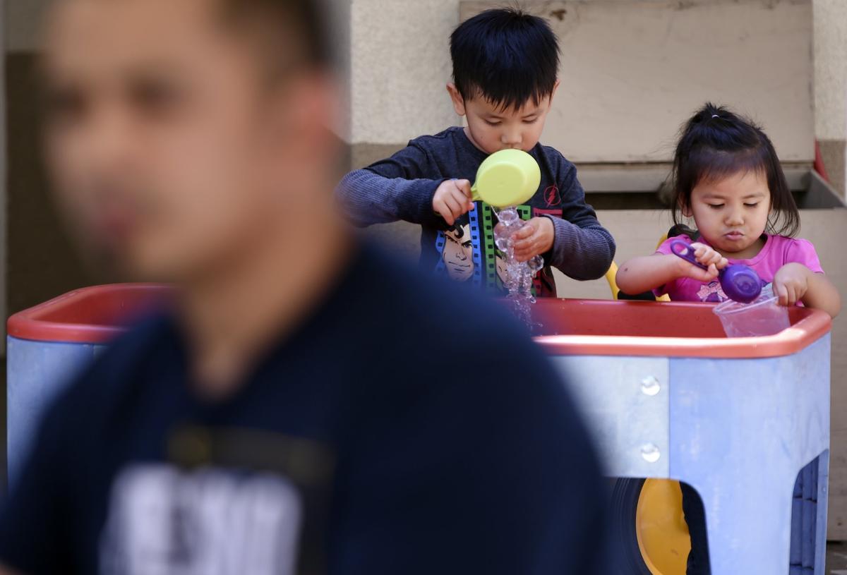 Jeevin, 4, and his sister Thanny, 2, play while their father Vanna In, left, talks about petitioning Gov. Jerry Brown for a pardon that he hopes will prevent his deportation to Cambodia. Photographed Friday, May 4, 2018 in Fresno.