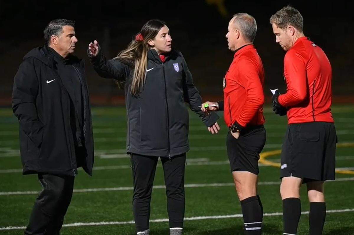 In an image from video, Buchanan HIgh School girls soccer coach Jasara Gillette, center, complains to game officials about racist taunts at her players coming from a fan in the home stands at Oak Ridge High School in El Dorado Hills at the Northern California Division 1 championship match on Saturday evening, March 5, 2022. Oak Ridge coach Rino Chimienti, left, was given a yellow-card warning moments later.