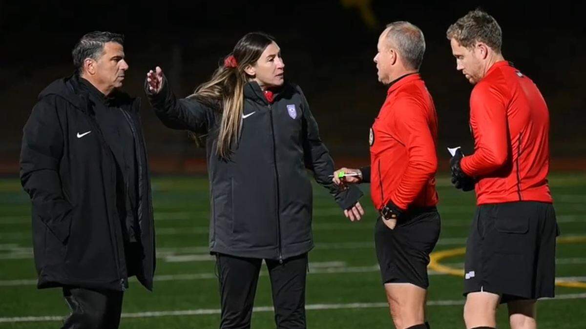 In an image from video, Buchanan HIgh School girls soccer coach Jasara Gillette, center, complains to game officials about racist taunts at her players coming from a fan in the home stands at Oak Ridge High School in El Dorado Hills at the Northern California Division 1 championship match on Saturday evening, March 5, 2022. Oak Ridge coach Rino Chimienti, left, was given a yellow-card warning moments later.