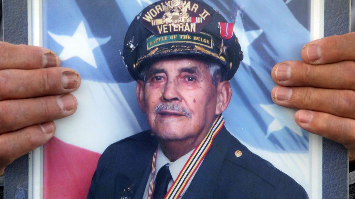 Henry Cedillo sostiene un retrato de su padre, el veterano del Ejército estadounidense Juan Cedillo.