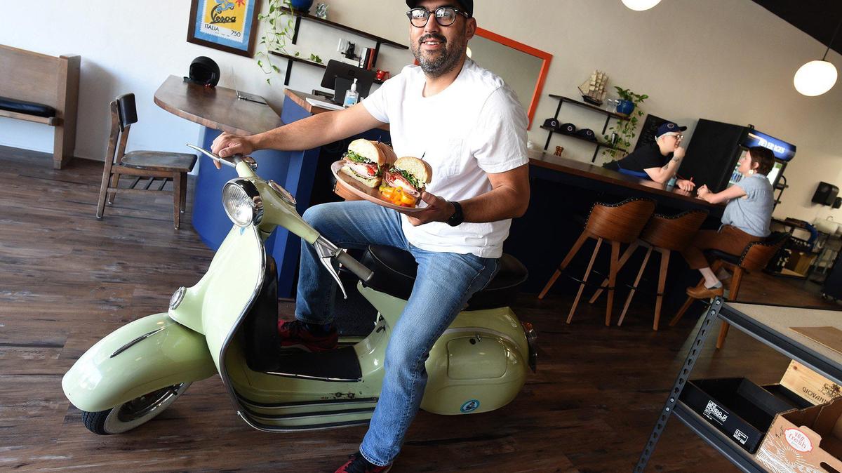 Carlos Moran aboard his 1964 Vespa scooter, at his MOTO Delicatessen and Bodega, 1916 N. Echo Ave.