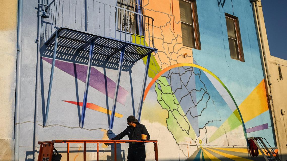 Fresno muralist Mauro Carrera works on a mural on a historic Chinatown building on China Alley in downtown Fresno on Friday, Dec. 16, 2022. The project is in conjunction with the Fresno Arts Council and the California High-Speed Rail Authority.