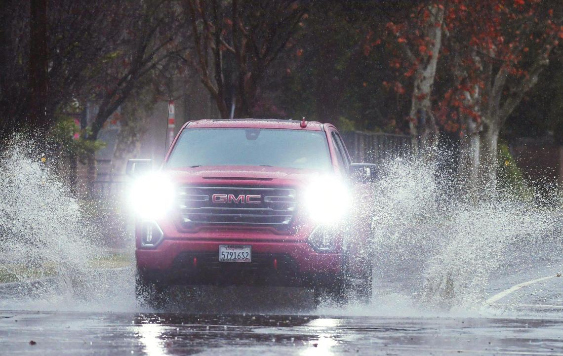 A truck splashes through standing water on Maroa Ave. at Clinton Ave. Tuesday, Dec. 27, 2022 in Fresno.