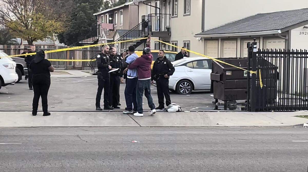 A man is pulled away by a friend from a shooting scene where one man died Thursday afternoon in east central Fresno.