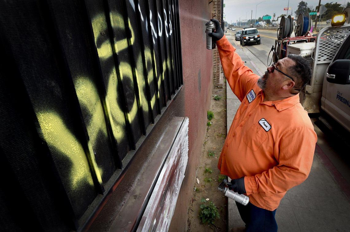Armed with spray paint cans, Frank Martinez of the city’s Graffiti Abatement team, covers the work of a tagger on a Parkway Drive motel, Jan. 13, 2022.