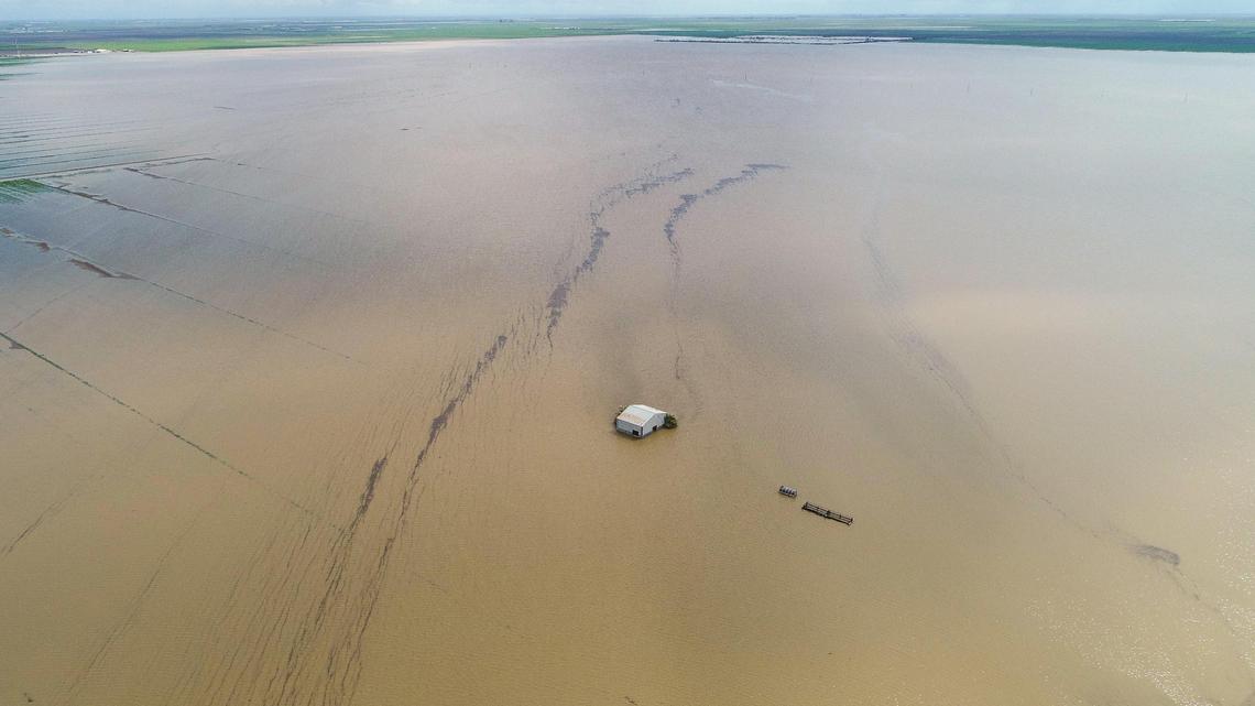 A barn is dwarfed by vast floodwaters in the old Tulane Lake basin area of Kings County south of Corcoran. The historic floods and the continuing aftermath has been one of the most impactful stories of the 2023.