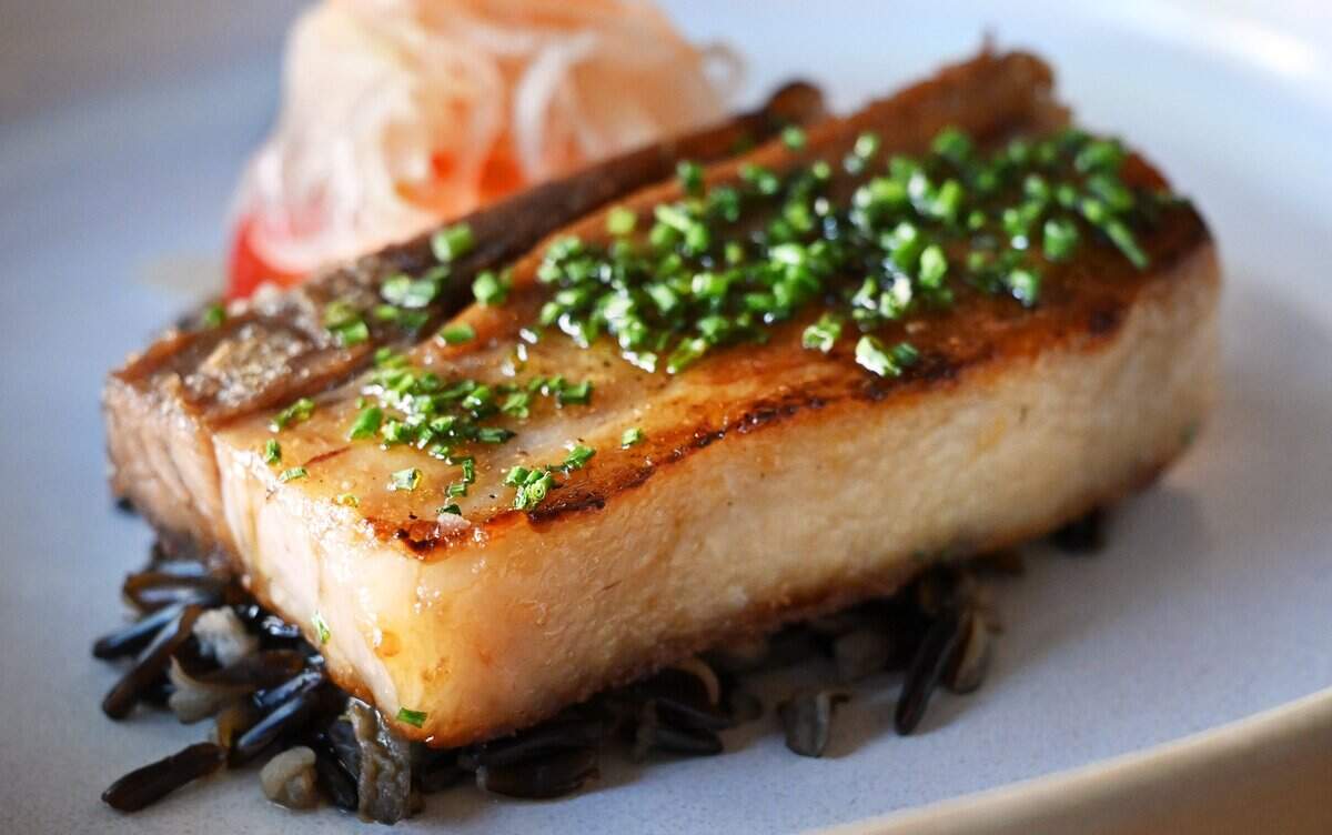 Second course item seared pork belly with kua txob wild rice, pickled papaya, sherry reduction and chives is served at Trelio Food & Wine Thursday, June 11, 2026 in Clovis.
