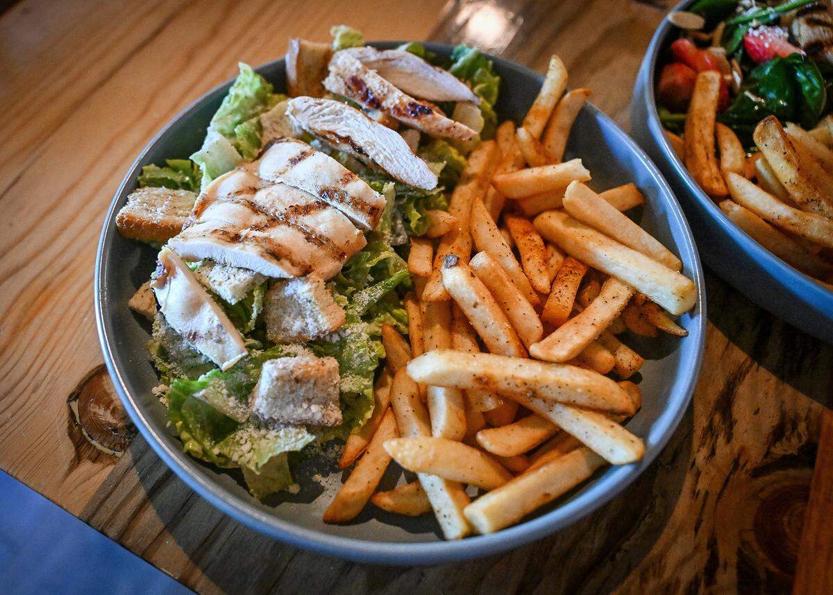 A half chicken Caesar salad is shown with french fries alongside a strawberry-spinach salad with chicken are options for the “girl dinner” meal at Ten Tavern on Willow and Nees in Clovis.